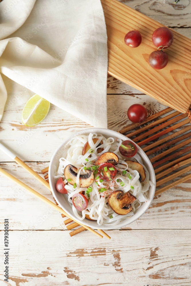 Bowl with tasty rice noodles and mushrooms on table