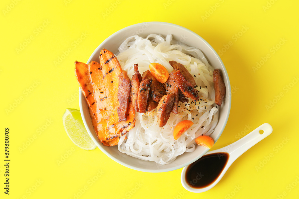 Bowl with tasty rice noodles and meat on color background