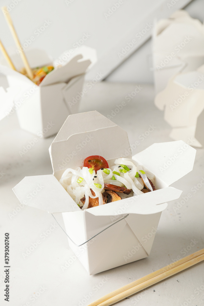 Box with with tasty rice noodles on white background