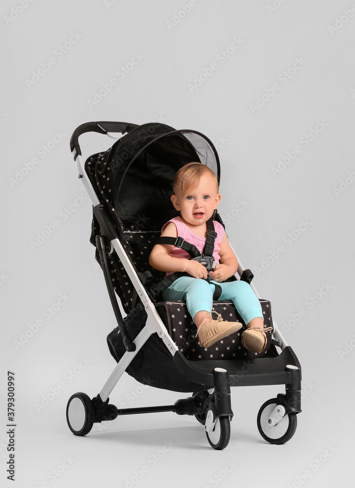 Cute little baby in stroller on light background