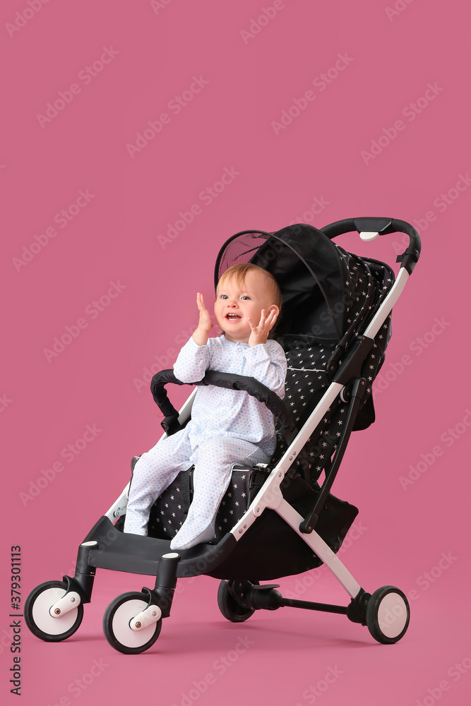 Cute little baby in stroller on color background