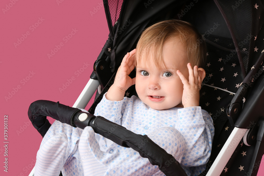 Cute little baby in stroller on color background