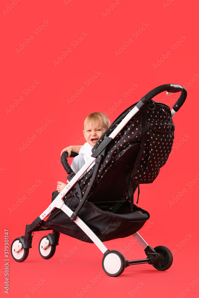 Cute little baby in stroller on color background