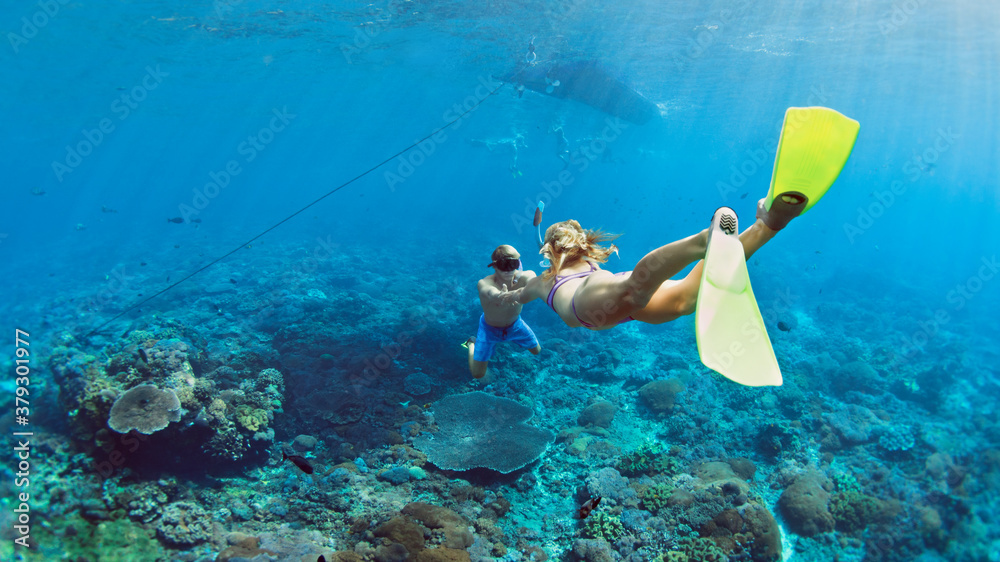 Happy family vacation. Young couple in snorkeling mask hold hand, free dive underwater with fishes i