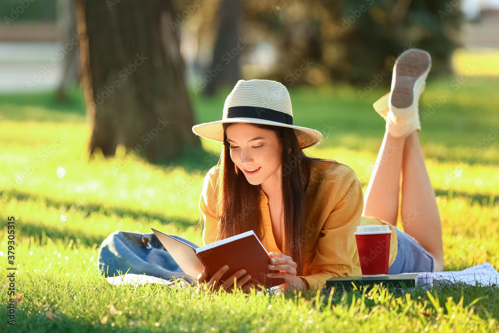 Beautiful young woman reading book in park