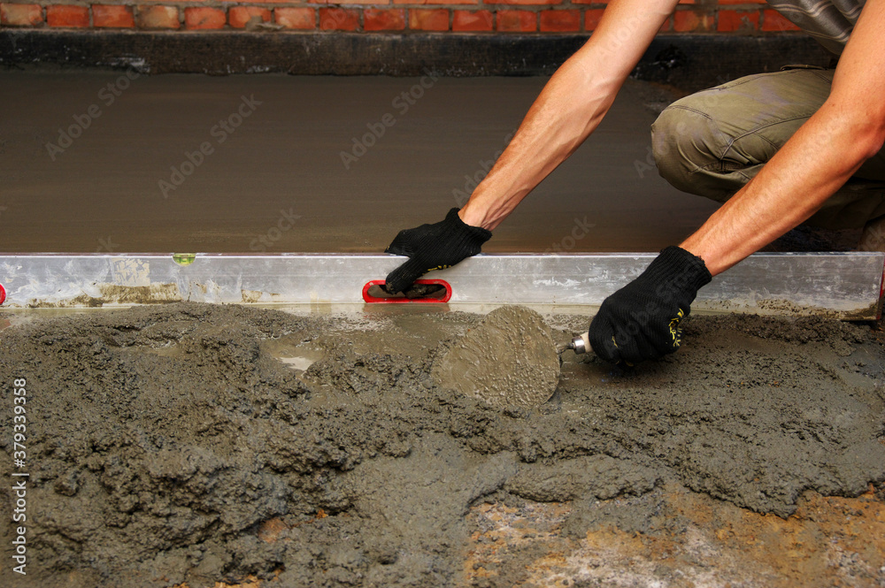 worker screeding indoor cement floor with screed