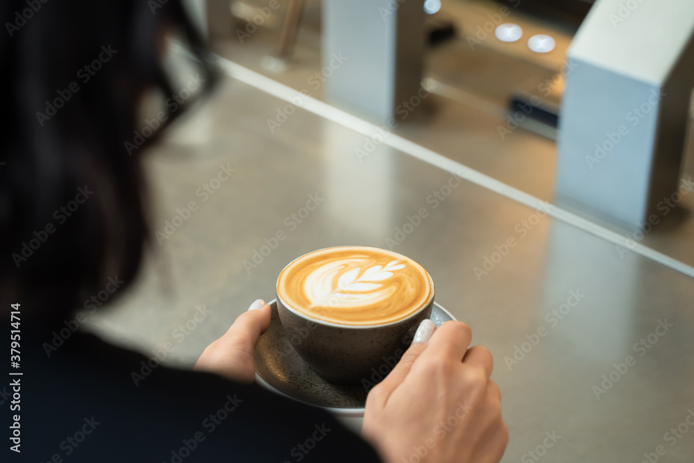 Beautiful customer in cafe restaurant holding cup of latte art coffee.