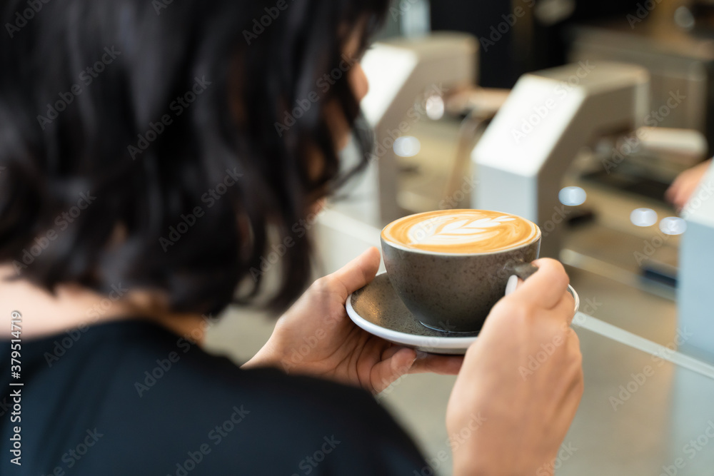 Beautiful customer in cafe restaurant holding cup of latte art coffee.