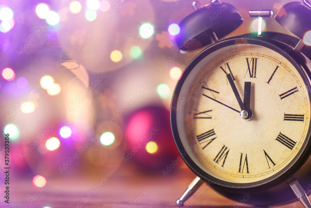 Alarm clock on table against blurred lights. Christmas time