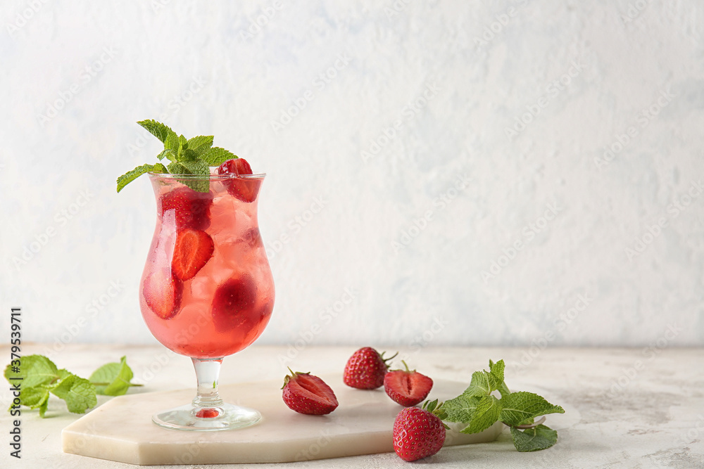 Glass of fresh strawberry mojito on light background