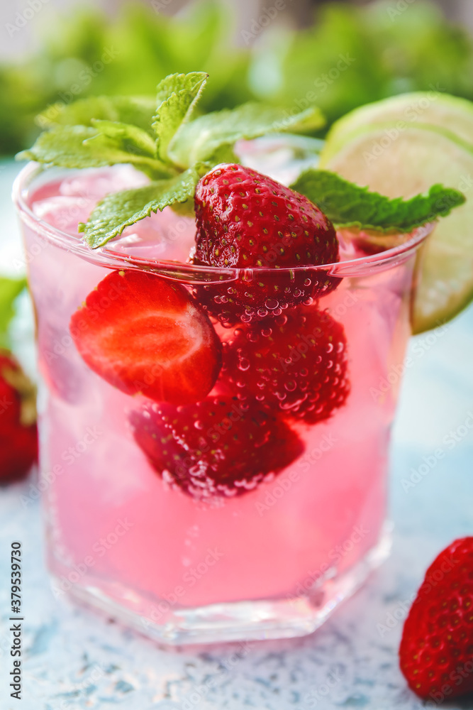 Glass of fresh strawberry mojito on color background