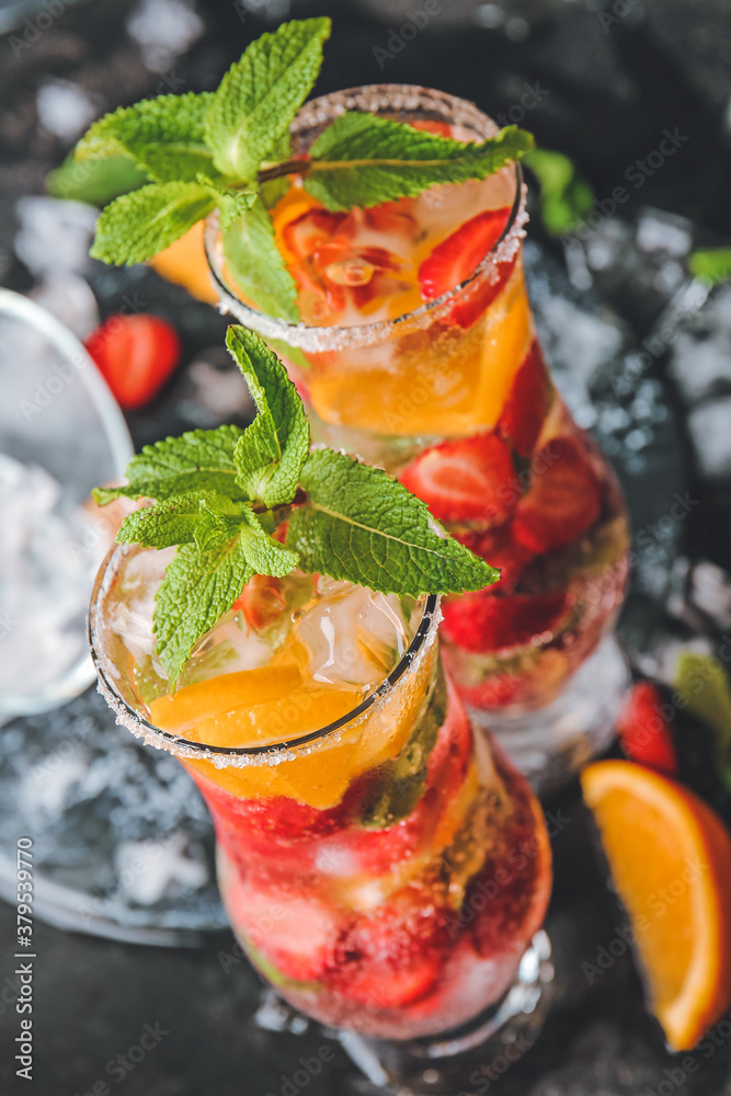 Glasses of fresh strawberry mojito on dark background