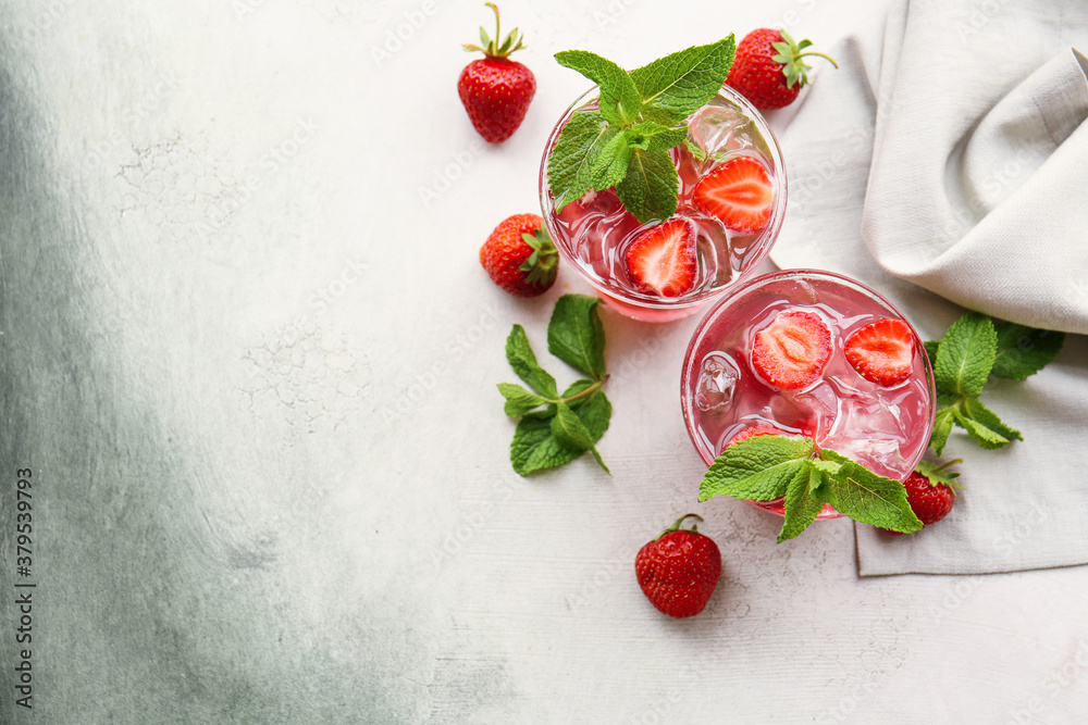 Glasses of fresh strawberry mojito on light background