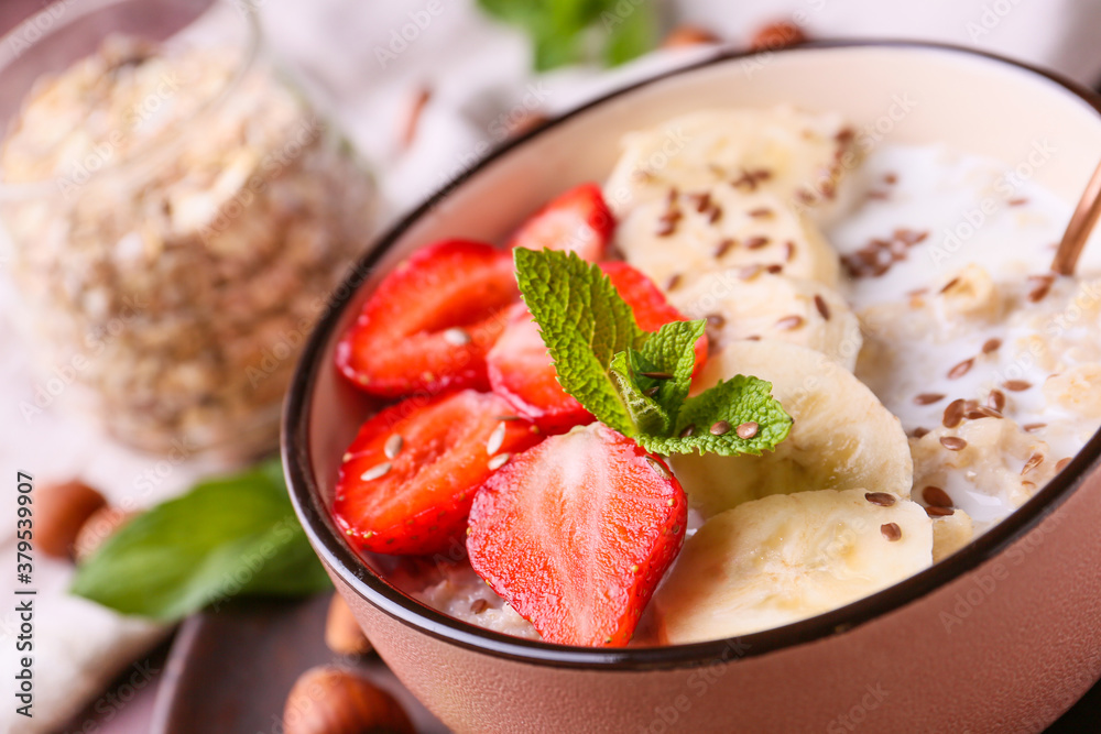 Bowl with tasty sweet oatmeal on table, closeup