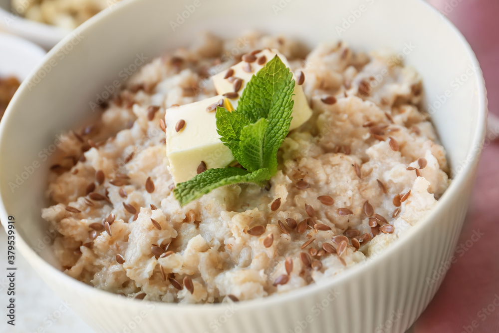 Bowl with tasty sweet oatmeal on table, closeup