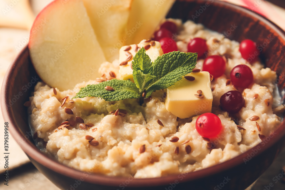 Bowl with tasty sweet oatmeal on table, closeup