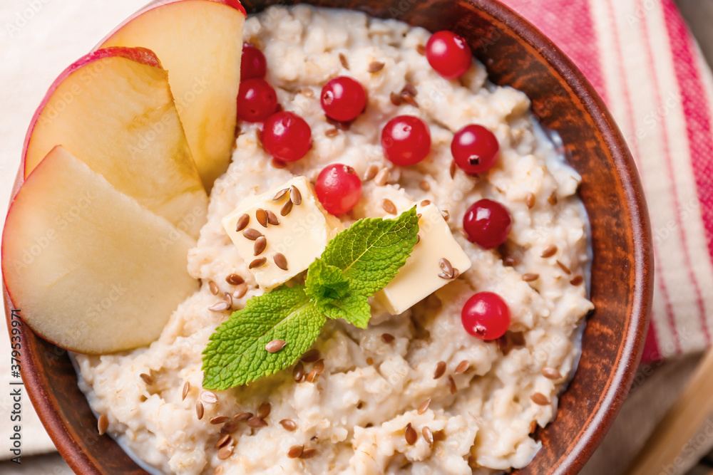 Bowl with tasty sweet oatmeal on table, closeup