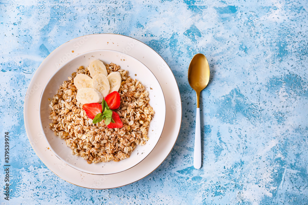 Bowl with tasty sweet oatmeal on color background