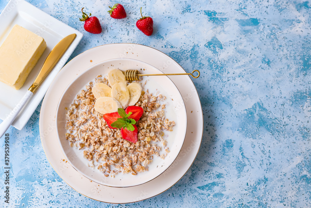 Bowl with tasty sweet oatmeal on color background