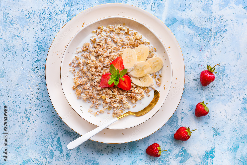 Bowl with tasty sweet oatmeal on color background