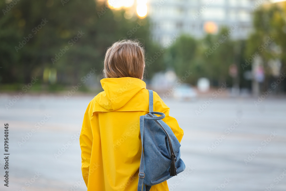 Beautiful young woman wearing raincoat outdoors