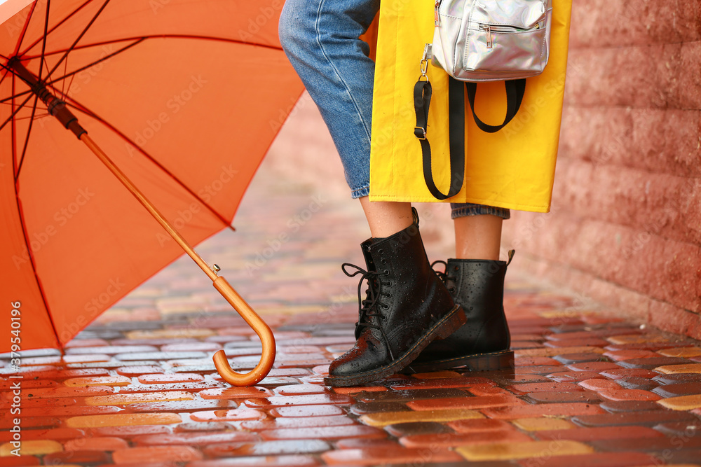 Beautiful young woman with umbrella wearing raincoat outdoors