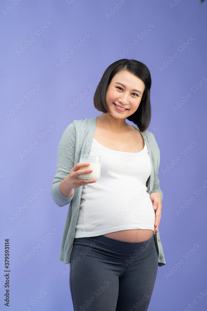 Pregnant mother drinks the milk on lilac background