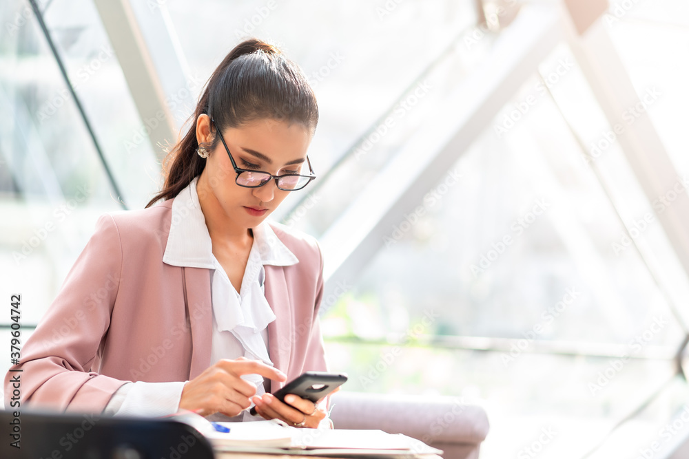 Business woman in pink suit seriously working on smartphone in the morning