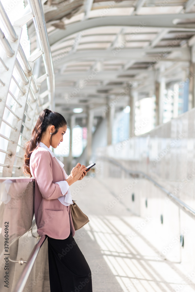 Smart business woman hold smartphone in pink suit