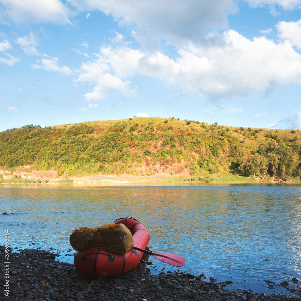 Orange packraft rubber boat with backpack on a river. Packrafting. Active lifestile concept