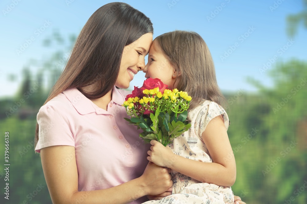 Mother and daughter with bouquet of flowers on blurred background.