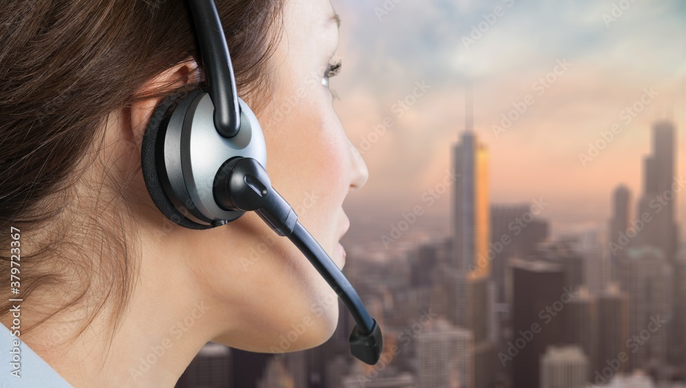 A young woman in headphones with a microphone working in a call center