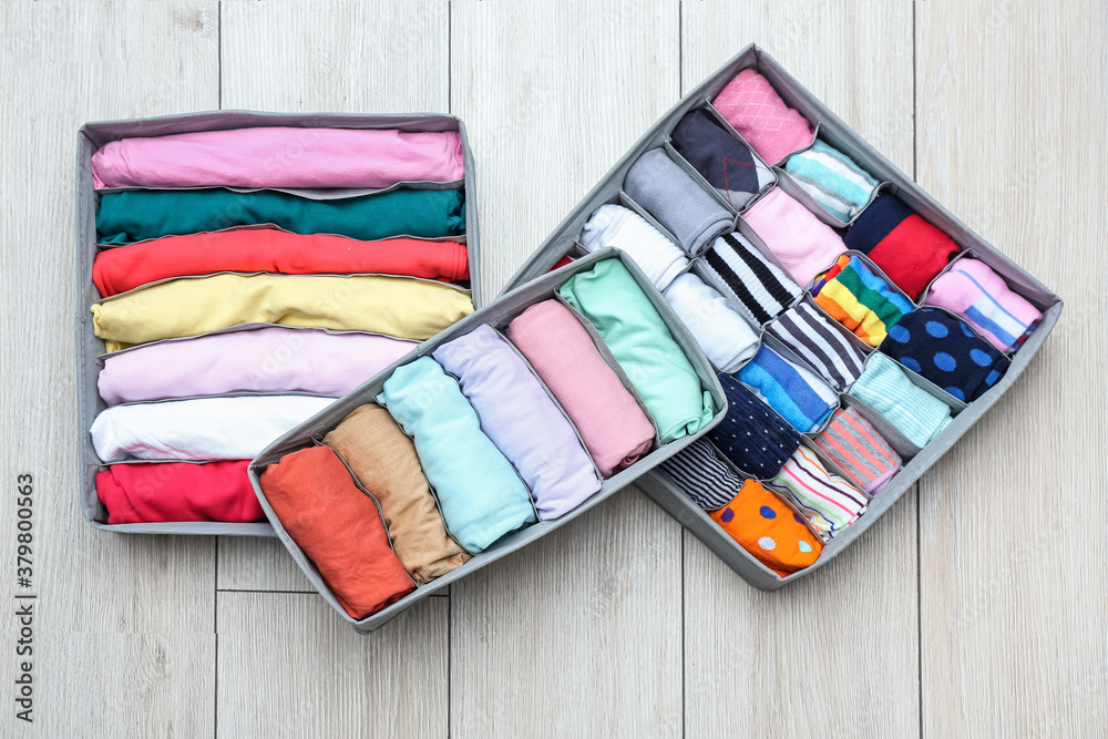 Organizers with clean clothes on wooden floor