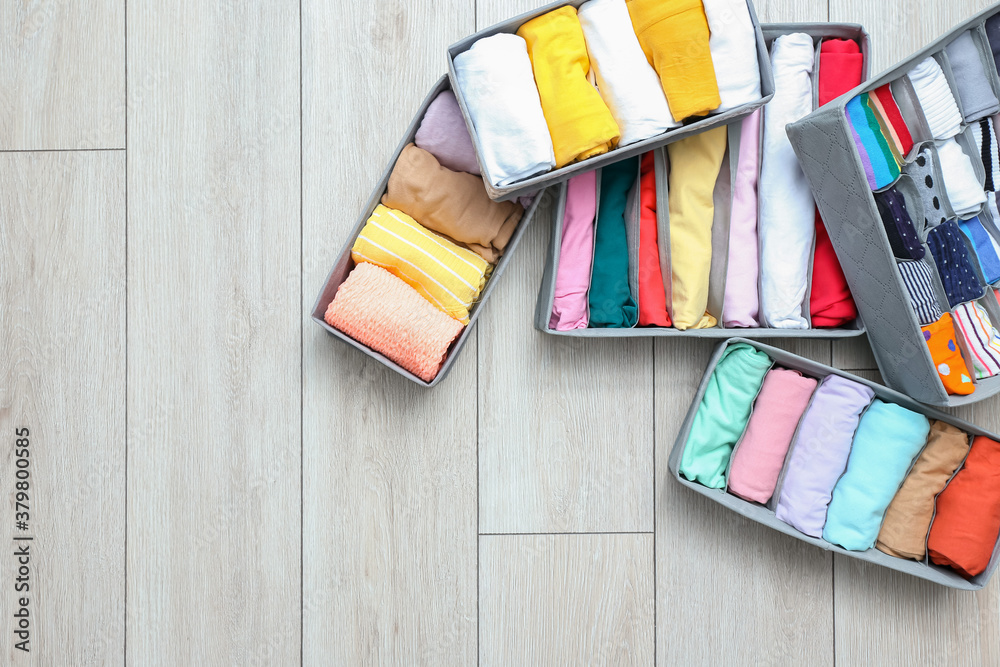 Organizers with clean clothes on wooden floor