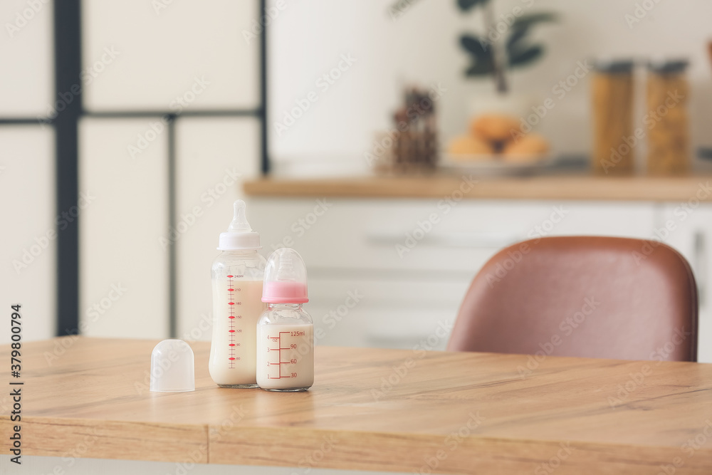 Bottles of milk for baby on table in kitchen