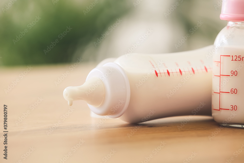 Bottles of milk for baby on table in room