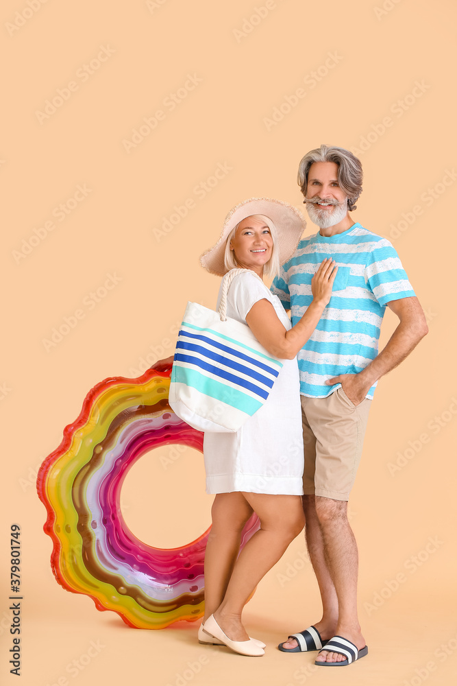 Mature couple with inflatable ring on color background