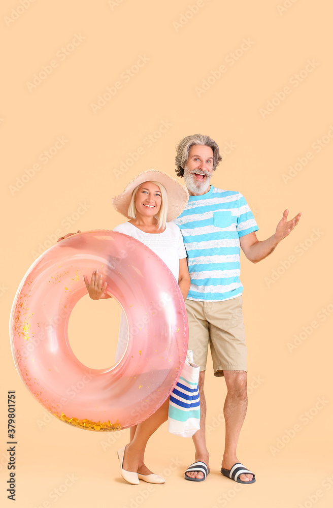 Mature couple with inflatable ring on color background