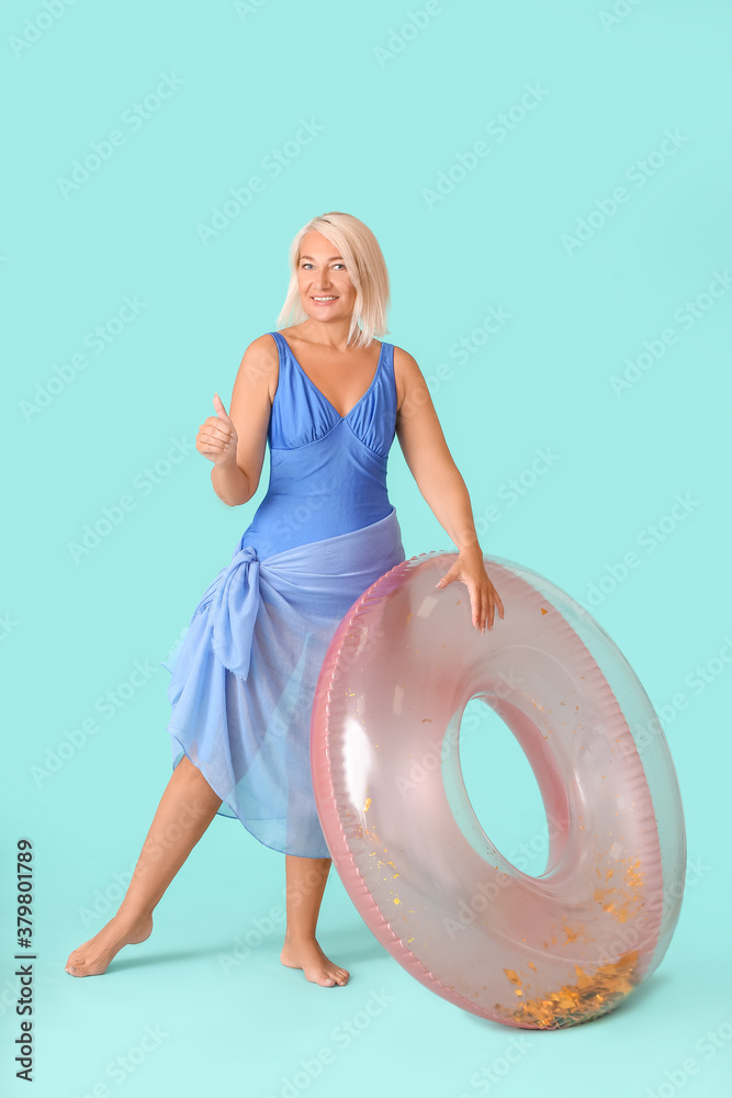 Mature woman with inflatable ring on color background