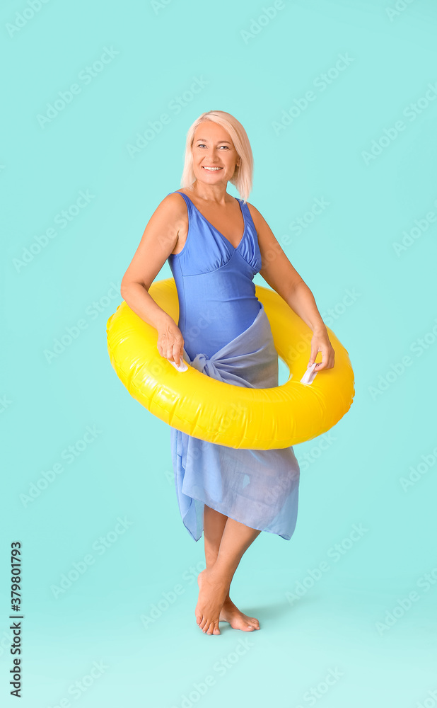 Mature woman with inflatable ring on color background