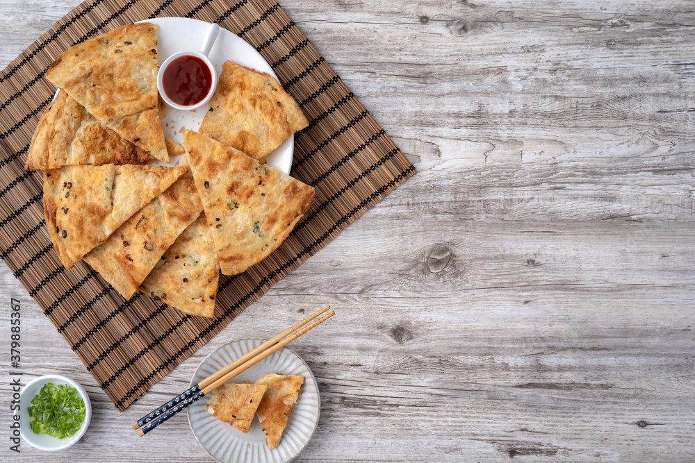 Taiwanese food - delicious flaky scallion pie pancakes on bright wooden table background, traditiona