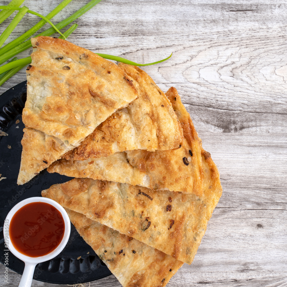 Taiwanese food - delicious flaky scallion pie pancakes on bright wooden table background, traditiona