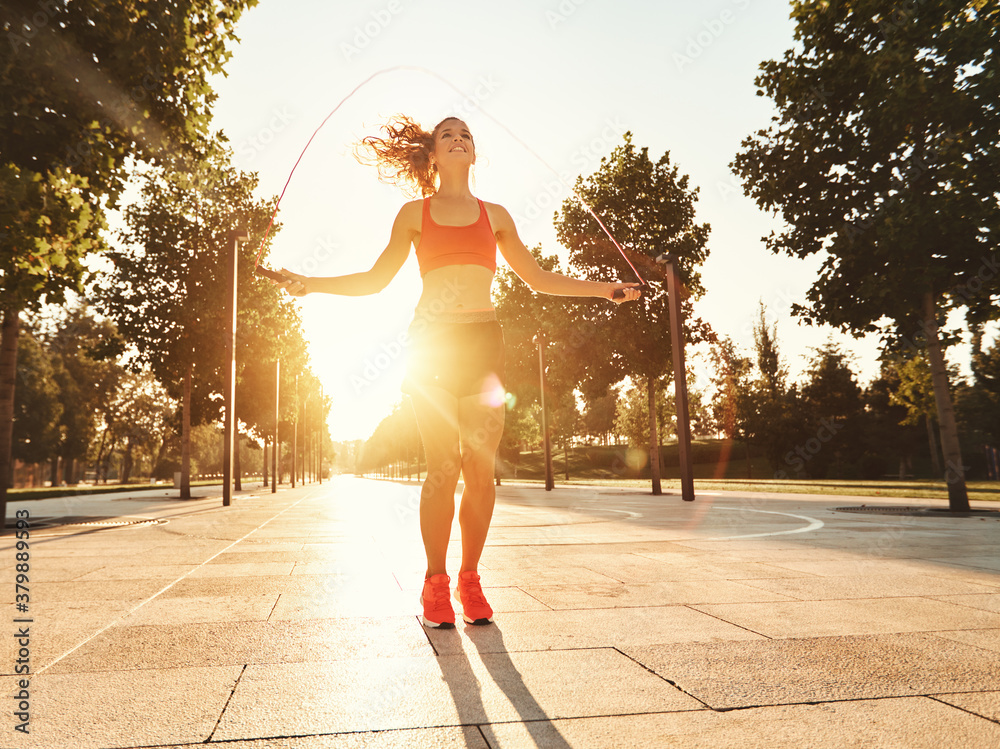 Athletic woman with jumping rope training in park.