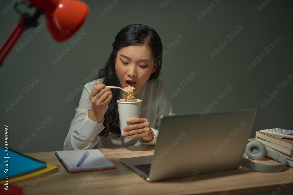 Happy young Asian girl sitting on desk work overtime, enjoy relax time.