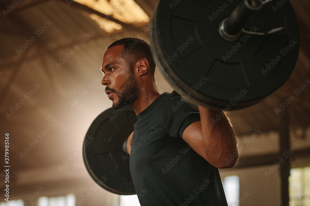 Fit man doing back squats with heavy weights