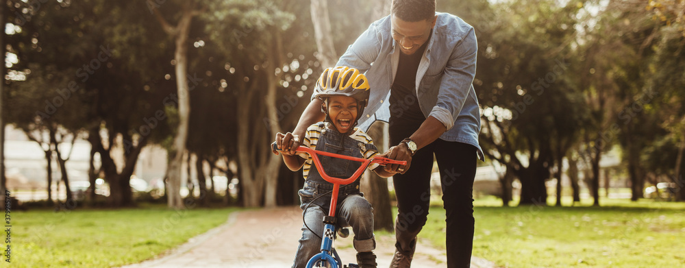 Father teaching his son cycling at park