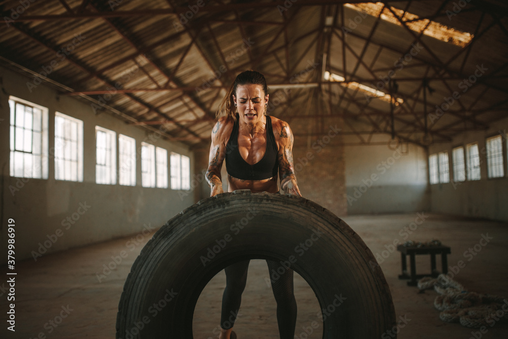 Muscular female working out with big tire