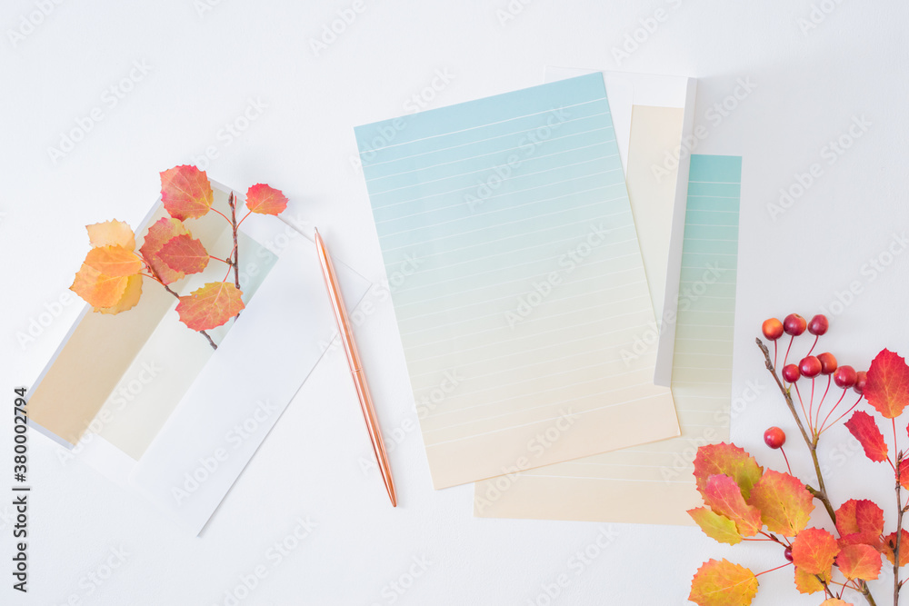 Workspace wedding invitation and envelope with colorful autumn leaves on a white background