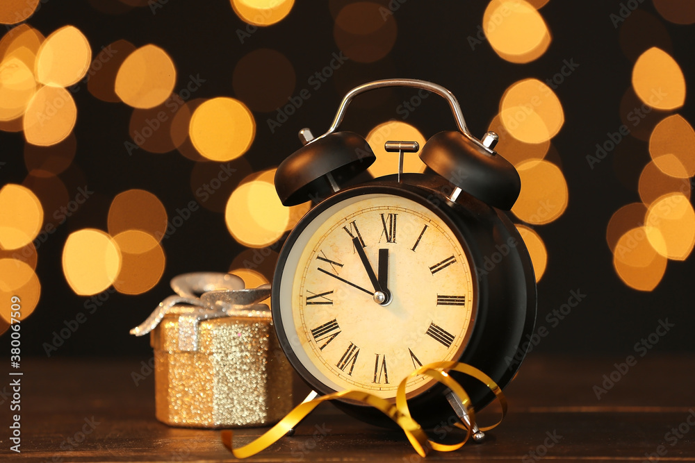 Alarm clock and Christmas gift against blurred lights