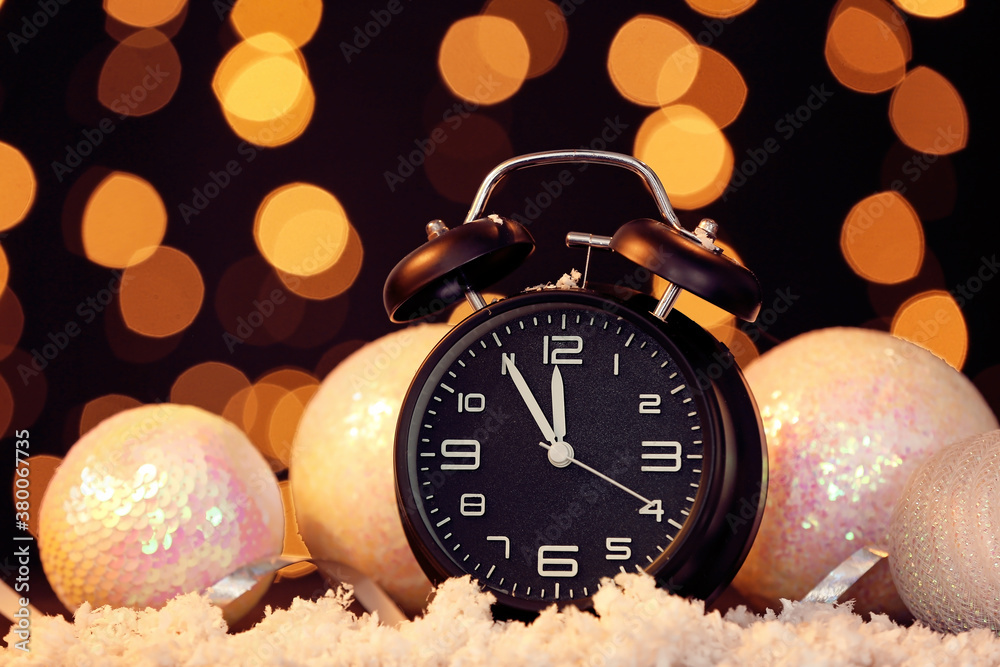 Alarm clock, snow and Christmas decor against blurred lights